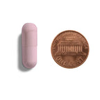 Size comparison of a Gut Harmony vegetarian probiotic capsule next to a penny to show easy-to-swallow small capsule size.